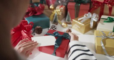 Kırmızı arka planda hediye kutusunu açan kız ellerini kapatır mısın? Geleneksel Noel kompozisyonu ve yeni yıl tatili sezonunun en az yaratıcılığı.