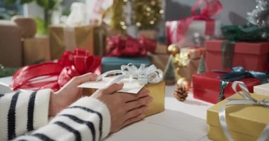Kırmızı arka planda hediye kutusunu açan kız ellerini kapatır mısın? Geleneksel Noel kompozisyonu ve yeni yıl tatili sezonunun en az yaratıcılığı.