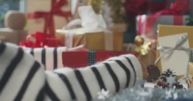 Hediye paketini paketleyen kızların ellerini kapatın. Kış Noel süsleri masanın üzerinde. Geleneksel Noel kompozisyonu ve yeni yıl tatili sezonunun en az yaratıcılığı.