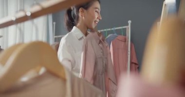 Neşeli, genç Asyalı bayan hediye almak için alışveriş yapıyor. Elbise ve giysi seçiyor. Alışveriş merkezindeki aynalı kumaş mağazasına bakın. Alışverişkolik kız, özel fiyat, tatil aktiviteleri yaşam tarzı konsepti.