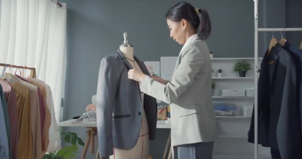 在现代工作室里 专注于年轻的亚洲服装制造商 时装设计师穿着套装站在模特上工作 女商人 时尚陈列室或工作室老板 小企业在裁缝概念中的作用 — 图库视频影像