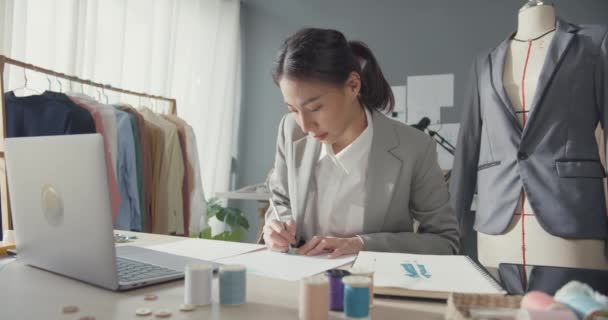 프로페셔널 아시아 사업가 디자이너는 노트북 컴퓨터와 테이블에 새로운 디자인 의상을 — 비디오