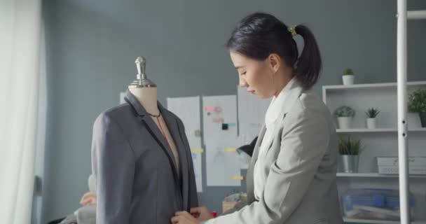 在现代工作室里 专注于年轻的亚洲服装制造商 时装设计师穿着套装站在模特上工作 女商人 时尚陈列室或工作室老板 小企业在裁缝概念中的作用 — 图库视频影像
