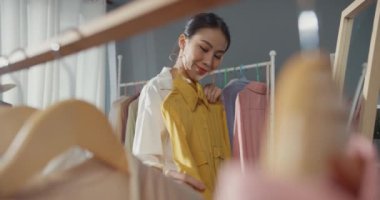 Neşeli, genç Asyalı bayan hediye almak için alışveriş yapıyor. Elbise ve giysi seçiyor. Alışveriş merkezindeki aynalı kumaş mağazasına bakın. Alışverişkolik kız, özel fiyat, tatil aktiviteleri yaşam tarzı konsepti.