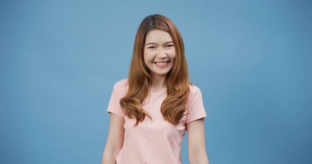 魅力的な陽気な若いアジアの女性は コンテンツと幸せなスタンドの肯定的な青の背景に隔離されたアップカジュアルなピンクの笑顔のショーの親指を身に着けています 品質と勧告の概念と満足 — ストック動画