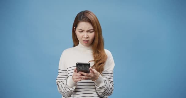 青の背景に隔離された店の提供の広告台とは異なり 右側には スマートフォンの外観を左に使用して動揺若いアジアの女性のセーターを着用 否定的なサインショーは親指を下に嫌い 拒絶概念 — ストック動画