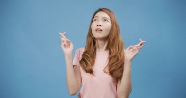 Çekici Asya 'lı genç bayan rahat giyiniyor. Özel anı bekliyor, dua ediyor, mavi arka planda izole edilmiş bir dilek tutuyor. Kadın sonuç beklentisi, başarı duygusu konsepti.