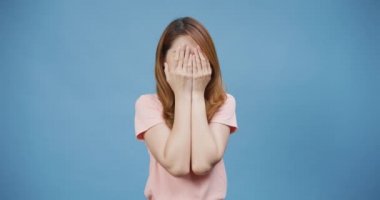 Çekici, neşeli, genç Asyalı bayan, günlük pembe gülümseme takın, gözlerinizi kapayın. Ellerinizle bir yuhalama oynayın. Yüzünüzü gösterin..