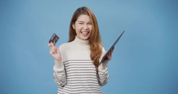 成功付款 年轻的亚洲女士穿着休闲装 网上购物 带着平板电脑和信用卡站在蓝色的背景上 妇女使用借记卡在网上银行付款 — 图库视频影像
