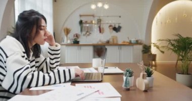 Freelance Asia lady casual wear using laptop online in kitchen at home office. Working from house, remotely work, distance education, social distancing, quarantine for coronavirus prevention.