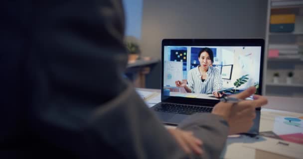 ノートパソコンを使ったアジアの女性は 自宅のリビングルームで夜間作業をしながら ビデオ通話の仕事について同僚に話します 自己分離 社会的距離 コロナウイルスの予防のための隔離 — ストック動画