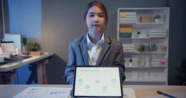 Güzel yönetici iş kadınının portresi... Gündelik kıyafetlerle kameraya bakıp gülümseyen, modern ofis iş yerinde mutlu. Genç Asyalı bayan evdeki video görüşmesinde meslektaşıyla konuşuyor..