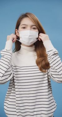 Genç Asyalı bayan koruyucu maske takıyor. Derin temiz hava alıyor. Koronavirüs salgını nedeniyle rahatlıyor. Karantina sona erdi, Tasasız konsept. Dikey ekran.