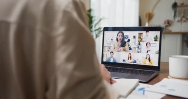 Genç Asyalı bayan dinleme lideri çeşitli çok ırklı iş arkadaşlarıyla çevrimiçi telefonda evdeki mutfakta dizüstü bilgisayarla konuşuyor. Kız öğrenci mesafesini evde, online buluşma konseptinde öğreniyor..