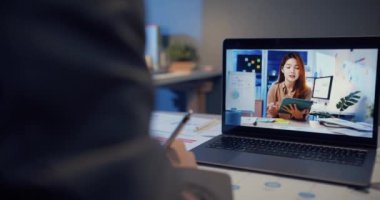 Dizüstü bilgisayar kullanan Asyalı iş kadını iş arkadaşlarıyla evdeki oturma odasındaki görüntülü görüşme planı hakkında konuşuyor. Gece aşırı yüklemeden, uzaktan, sosyal mesafeden, koronavirüs için karantinadan..