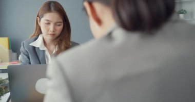 Genç Asyalı iş kadınları masadaki dizüstü bilgisayarlarını kullanarak iş yerindeki ofis masasında oturarak iletişim kuruyorlar. Uzak webinar, internet teknolojisi, yaşam tarzı sosyal uzaklık ve Coronavirüs 'ten sonra çalışma.