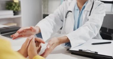 Beyaz üniformalı genç Asyalı kadın doktorların yakın çekimleri sırasında sağlık kliniğinde ya da hastane ofisinde otururken hasta omzuna dokunmayı tartışırlar. Psikolojik yardım kavramı.