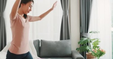 Genç, çekici, güzel, formalı, Asya 'lı bir kadın spor giyim pratiği yapıyor. Yeni başlayanlar için oturma odasında egzersiz yapıyor. Spor salonu olmadan ev karantinası fitness antrenmanı.