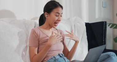 Dizüstü bilgisayar kullanan Asyalı iş kadını, oturma odasından çalışırken iş arkadaşlarıyla görüntülü görüşme planı hakkında konuşuyor. İş yerinde uzaktan, sosyal uzaklık, korona virüsünün önlenmesi için karantina.