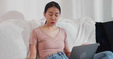 Dizüstü bilgisayar kullanan Asyalı iş kadını, oturma odasından çalışırken iş arkadaşlarıyla görüntülü görüşme planı hakkında konuşuyor. İş yerinde uzaktan, sosyal uzaklık, korona virüsünün önlenmesi için karantina.