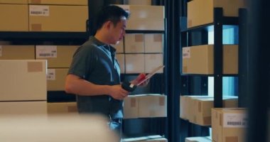 Asian businessman use barcode scanner scan paper box in shelf and put data in digital tablet cut stock online data information detail for express delivery at warehouse. Startup small business concept.