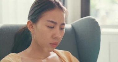 Young asia female girl or university student sit on sofa chair with computer laptop feel eyes tired take a rest and rubbing for relax from overwork in living room at home. Work life balance concept.