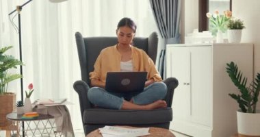 Young attractive asian female girl or university student sit on sofa chair with computer laptop feel focus and serious look on screen and thinking idea work report in living room at cozy home.