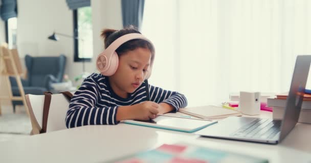 Ασιατική Κοριτσάκι Πουλόβερ Φορούν Ακουστικά Κάθονται Μπροστά Από Γραφείο Σημειωματάριο — Αρχείο Βίντεο