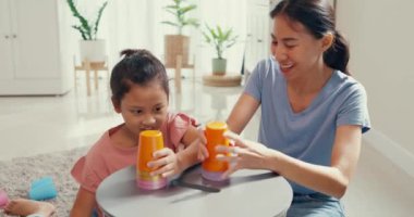 Asian toddler little girl with mom sit on carpet with happy moment playing colorful stacks cup toy on table in living room at home. Family spend fun time together, Creative lifestyle for kid concept.