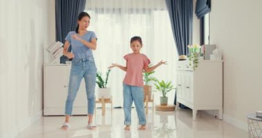 Asian toddler little girl daughter with mother use dancing together in front of camera record video having fun happy in living room at home. Family spend time together, Creative lifestyle concept.