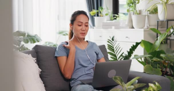 Ung Asiatisk Kvinde Med Afslappet Slid Øretelefon Sidder Sofaen Bærbare – Stock-video