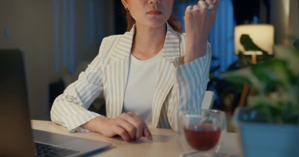 閉鎖若いアジアのビジネスマンの女性は 自宅の夜に居心地の良いリビングルームの屋内植物でノートパソコンやティーカップカウントやタイピングのアイデア報告書と机の正式な座面を着用してください 残業の概念 — ストック動画