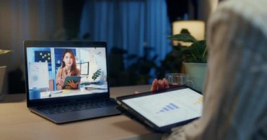 Genç Asyalı iş kadını resmi giyiniyor. Tablet tutucu Stylus 'la birlikte masanın önünde oturuyor. Ev gecesinde iş arkadaşıyla birlikte samimi oturma odasında laptoplu ekran video toplantısına odaklanıyor. Fazla mesai konsepti.