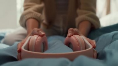 Beyaz krem pijamalı Asya 'lı kız pembe kulaklık takıyor mutlu dans ediyor, gülümsüyor ve sabahları pencereden yatak odasındaki kameraya bakıyor. Kadın sabah titreşimleri konsepti.