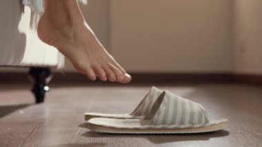 Yakın plan Asyalı bir kız, beyaz pijamalarıyla yatağa basar, terlik giyer, pencereyi açar, temiz, huzurlu bir sabah ışığı altında, yatak odasındaki boş zemine uzanır. Kadın yaşam tarzı konsepti.