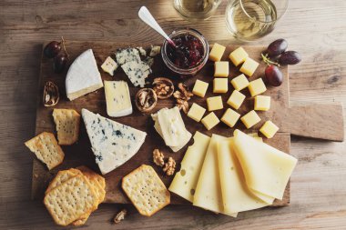Cheese plate with different arts of cheese grape and nuts served on wooden board. 