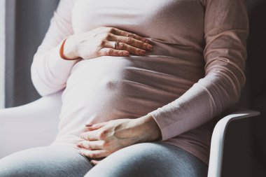 Unrecognizable Pregnant woman touching belly being home enjoying pregnancy. Lifestyle. Maternity concept. 