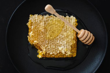 Honeycombs with fresh honey and honey spoon on dark background. Closeup