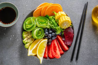 Vegan buddha bowl with vegetables and fruits served in bowl on grey background. Closeup