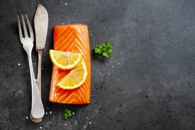 Raw salmon fillet on dark stone background. Closeup
