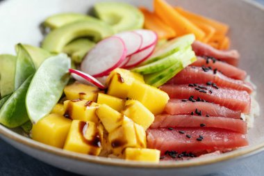 Healthy raw Tuna bowl with vegetables served on plate. Closeup 