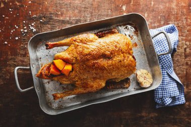 Baked roasted duck with vegetables on pan on old wooden background. Top View. 