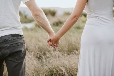 Happy young couple holding hands together on nature background. Love concept