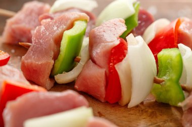 Tasty appetizing raw meat skewers on wooden vintage background. Closeup