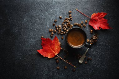 Autumn concept background with autumn leaves and coffee served in cup on dark background. 