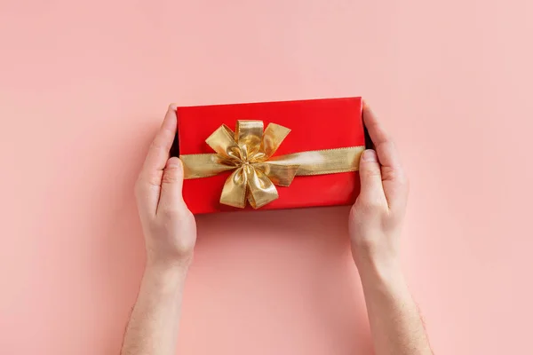 Man Holding Giftbox Golden Ribbon Hands Pink Background —  Fotos de Stock