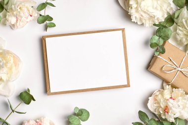 Fotokopi alanı, hediye kutusu, beyaz şakayık çiçekleri ve beyaz dallı okaliptüs dallarıyla tebrik kartı modeli.