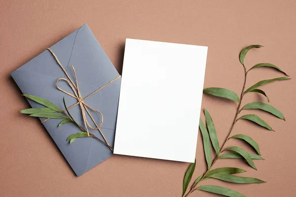 Zaproszenie lub kartka okolicznościowa makieta z kopertą i naturalnymi gałązkami eukaliptusa. — Zdjęcie stockowe
