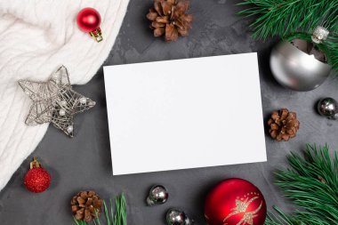 Noel tebrik kartı, şenlikli süslemeler ve kozalaklı çam ağacı dalları.