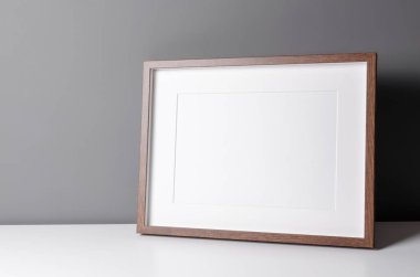 Manzara ahşap çerçeve modeli, resim ve parmak izi sunumu gri duvardaki beyaz masada. Minimalist iç tasarım.